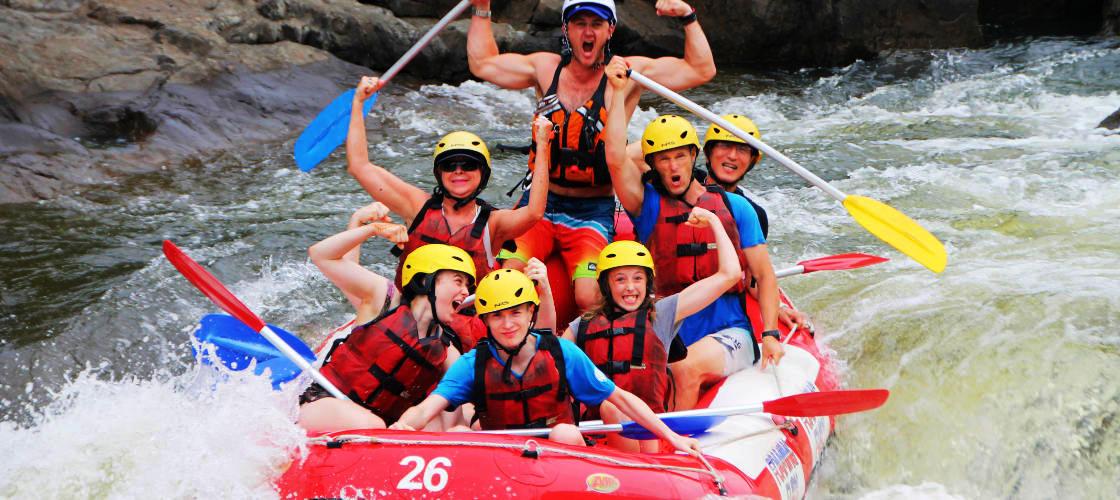 Tour group smiling for photo while whitewater rafting in Cairns