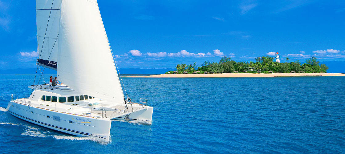 Sail boat cruising past island