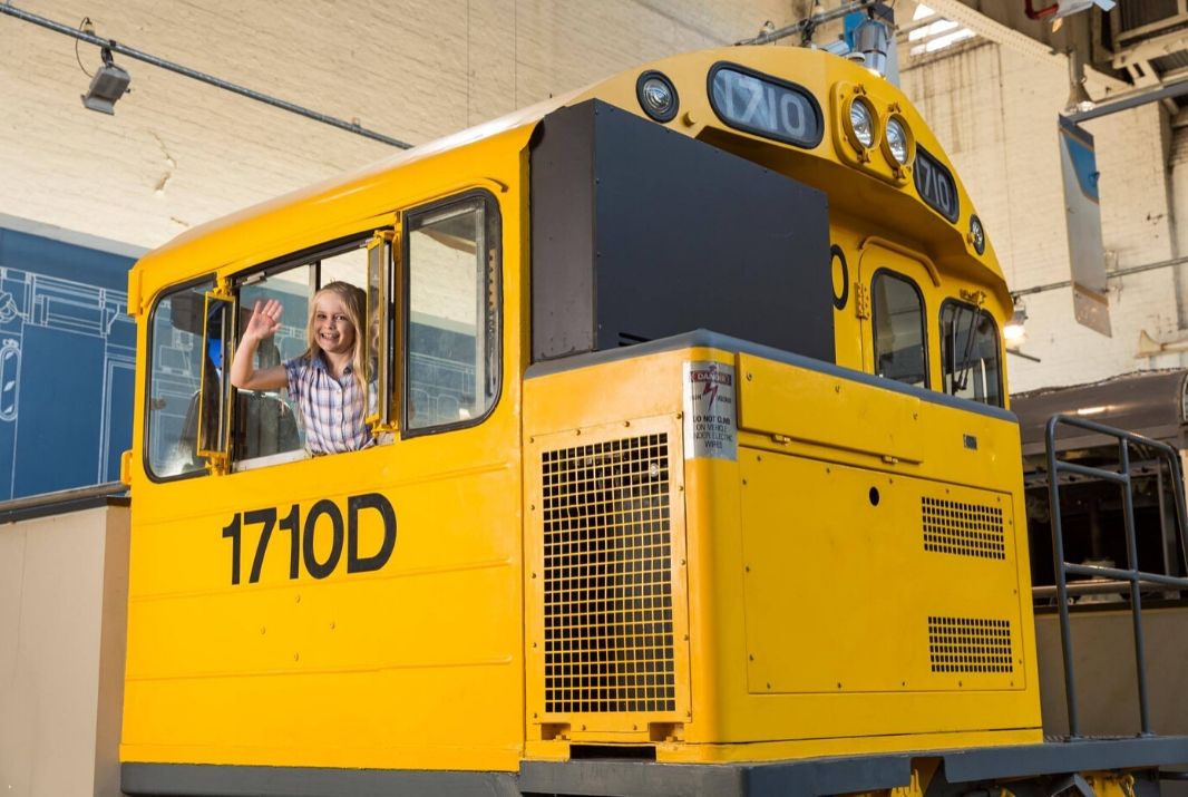 Little girl hanging out window in train playground
