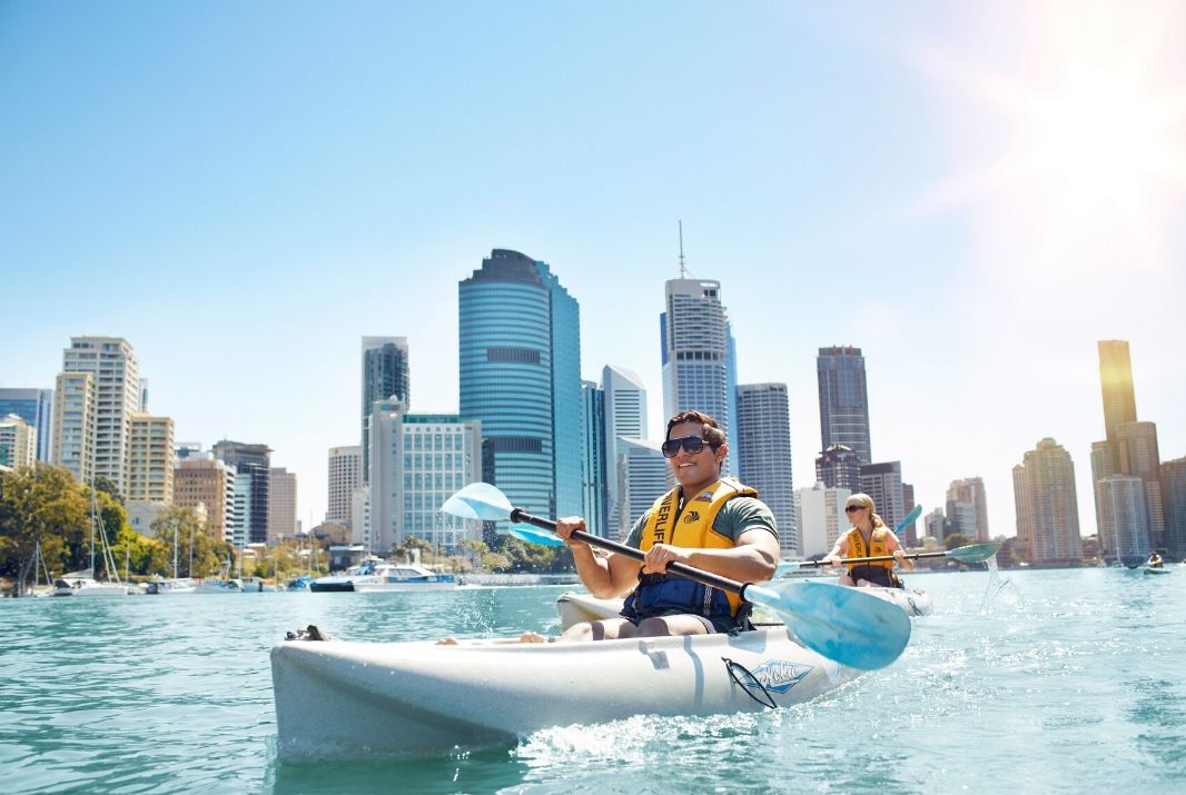 Couple kayaking through Brisbane River on a sunny day