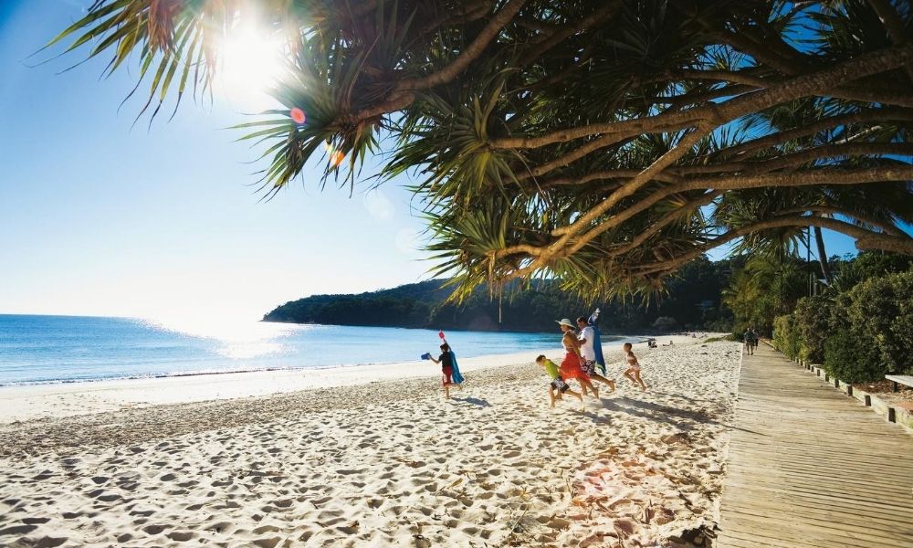 Family running onto beach Sunshine Coast