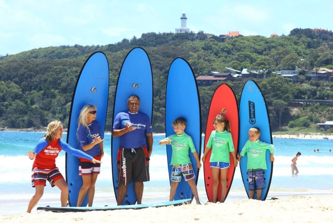 Family standing in front of surfboards for surfing lessons Byron Bay