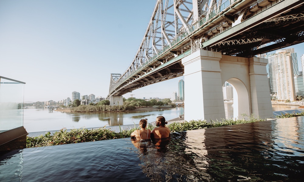 Couple in The Fantauzzo Hotels pool in Brisbane overlooking Story Bridge