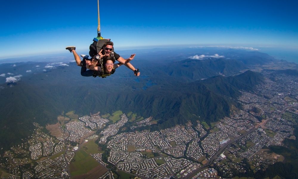 Woman tandem skydiving over Cairns mountains
