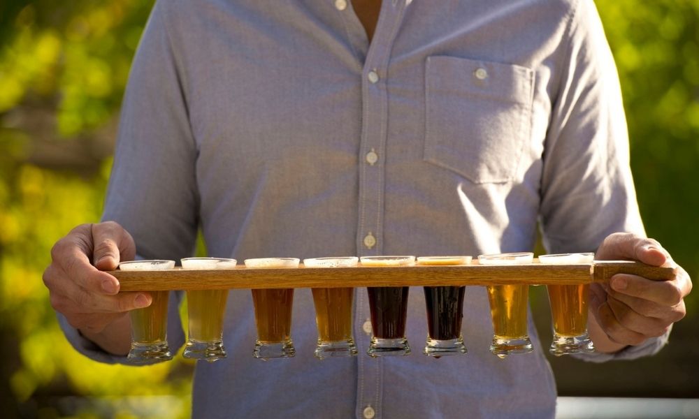 man carries a paddle of beers during an Adelaide Hills Brewery Tour
