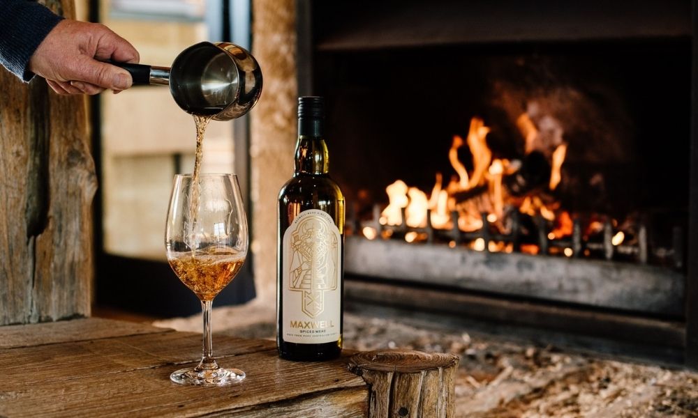 Man pours a glass of wine in front of a warm fireplace in McLaren Vale