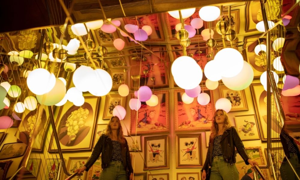 Woman walks through the Darenberg cube art gallery admiring the artworks on wall