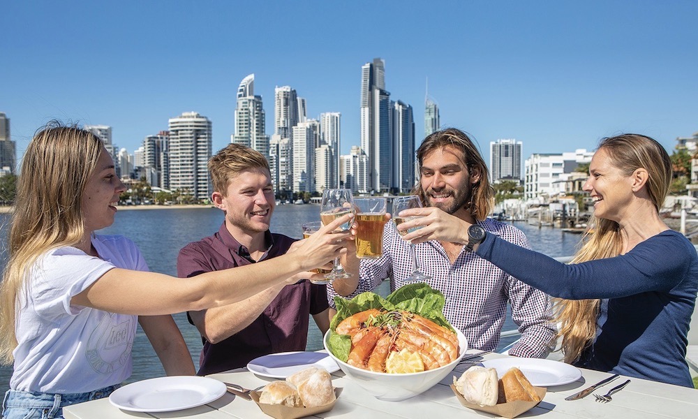 A group of friends enjoy lunch on a Gold Coast canal cruise with the skyline in the background